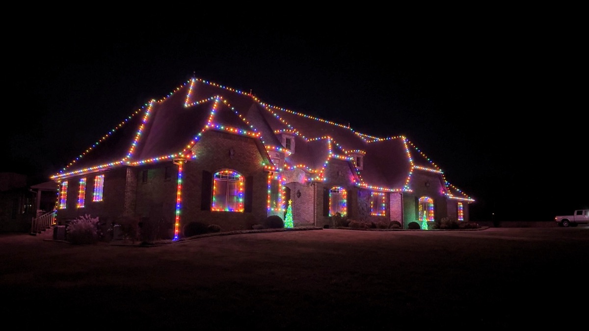 Large brick home outlined in multicolor lights along rooflines and windows